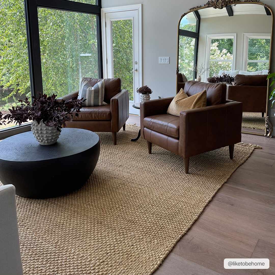 Living room with brown leather chairs, a jute rug, and decorative elements.